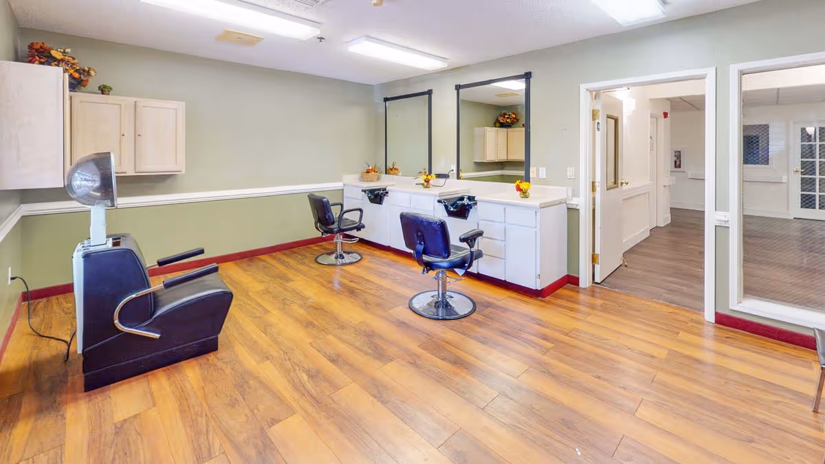 Interior salon room with styling chairs, a hooded hair dryer, mirrors, and cabinetry on wood-look flooring.