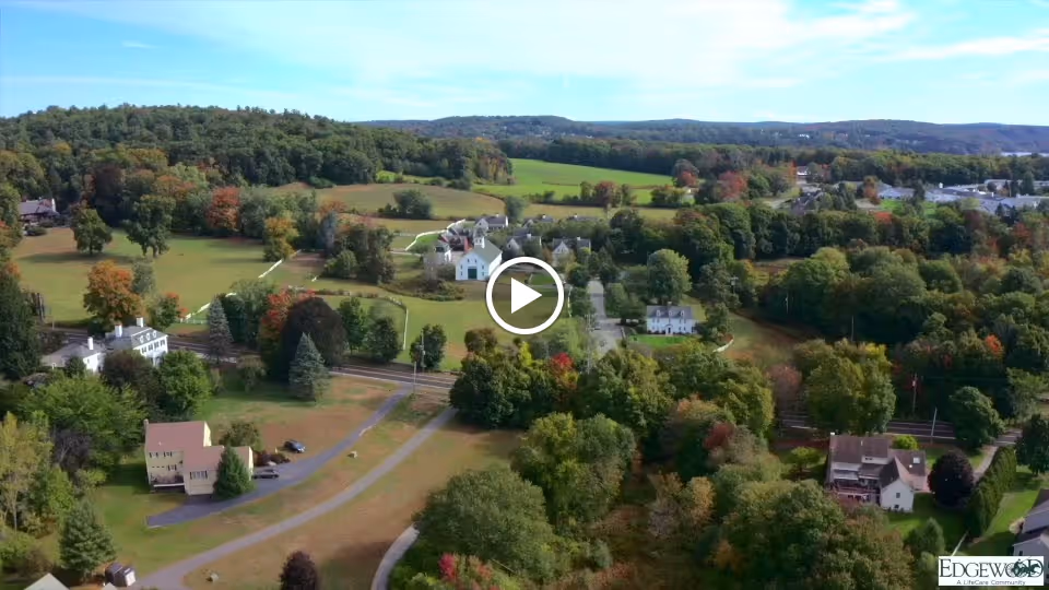 Aerial view of a rural campus with houses, roads, fields and wooded areas.