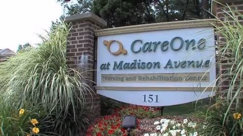 The CareOne at Madison Avenue exterior sign sits beside a brick pillar with flowers.