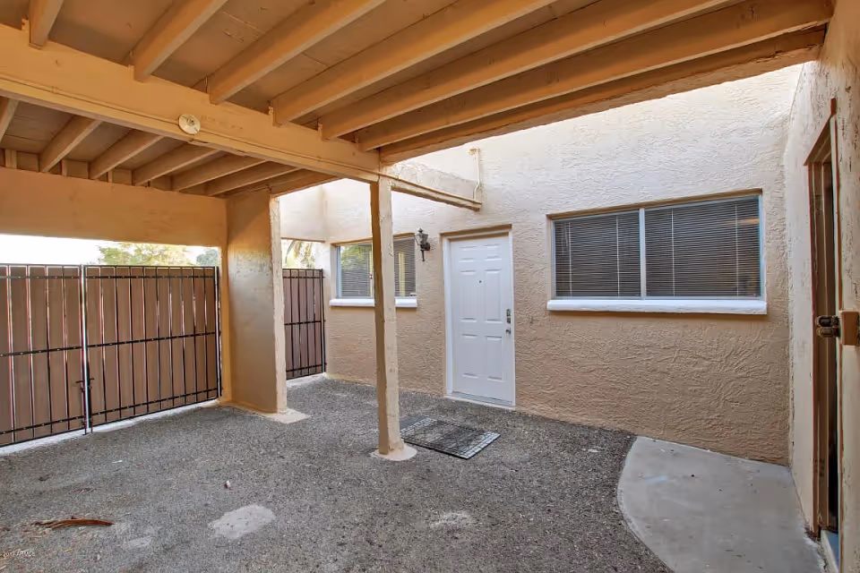 Covered courtyard/patio with a white door and windows beneath exposed wooden beams.