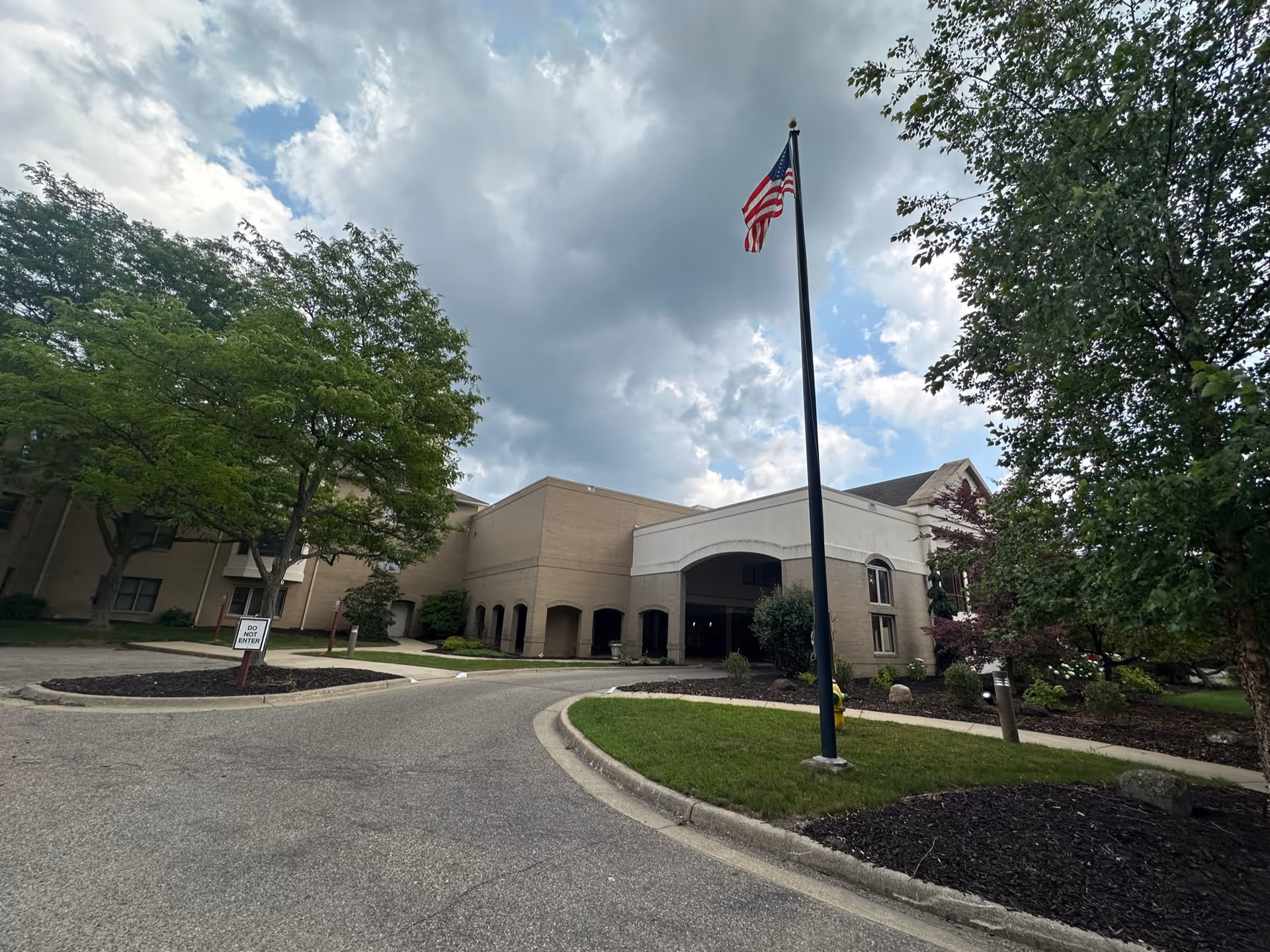 StoryPoint Kalamazoo senior living facility exterior with entrance, flagpole, and surrounding trees.