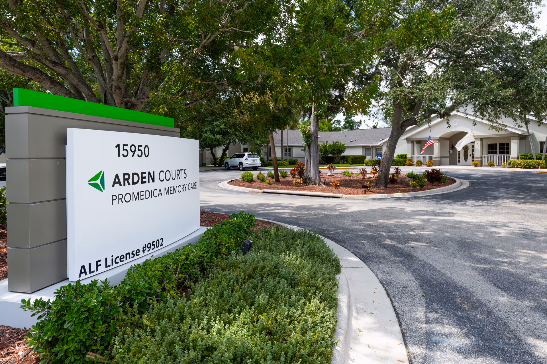 Roadside sign for Arden Courts ProMedica Memory Care at 15950 with a circular driveway, landscaping, and the facility entrance visible.