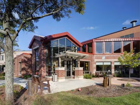 Brick exterior of a senior living facility with glass entrance and landscaped frontage.