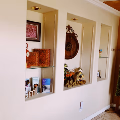Interior hallway with recessed wall shelves displaying decor and a welcoming plant.