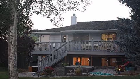 Exterior view of Shepherds Gate senior living facility with a wooden upper deck and outdoor seating.