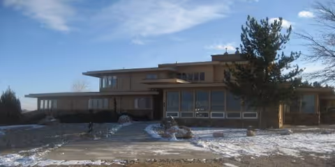 A modern care home exterior with large windows and light snow.