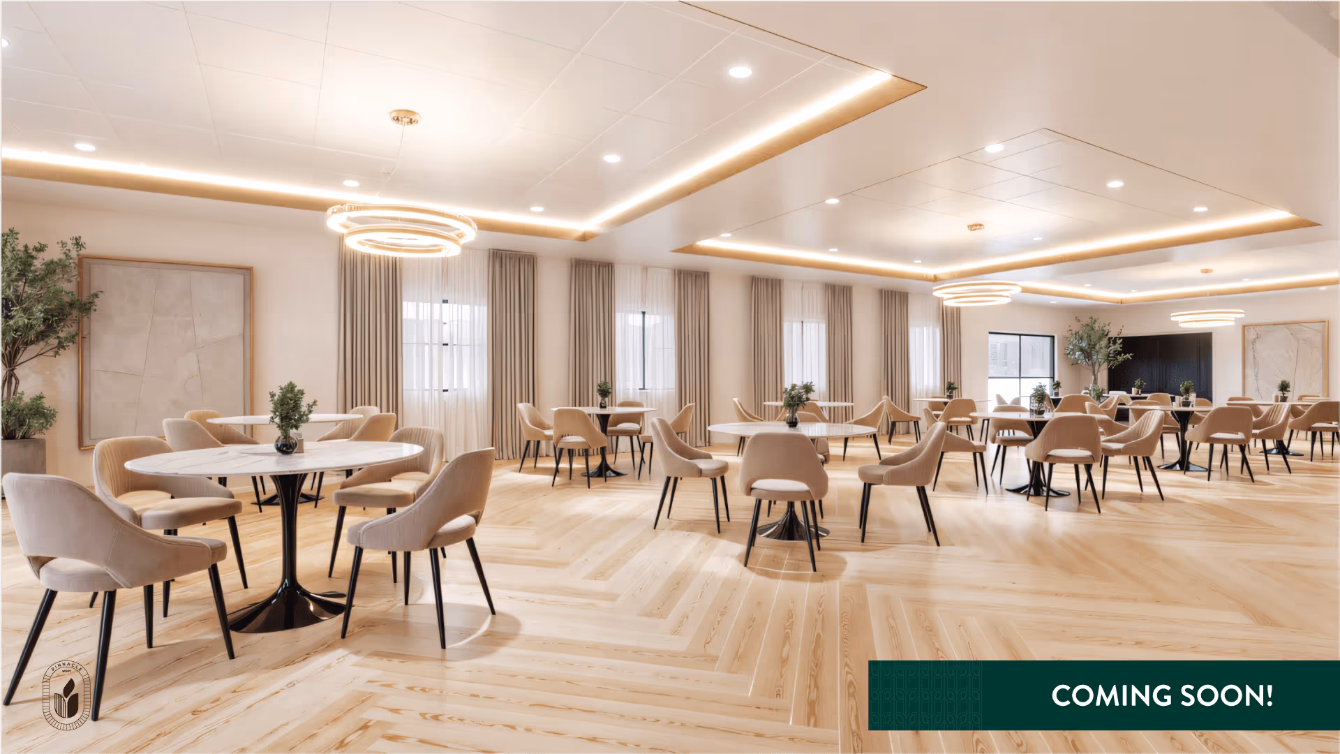 A spacious, modern dining room with multiple round tables surrounded by beige upholstered chairs. The room features light wood flooring arranged in a herringbone pattern, large windows with beige curtains, and contemporary circular ceiling lights. There are potted plants and framed artwork on the walls, creating a welcoming atmosphere.