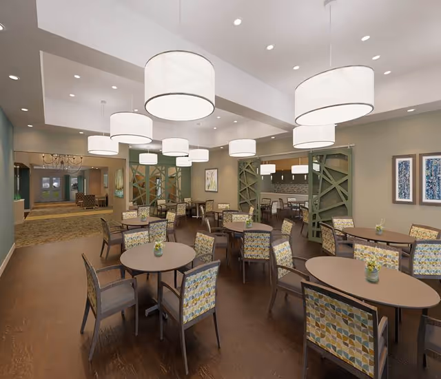 Spacious dining room with round tables and patterned upholstered chairs under large circular pendant lights.