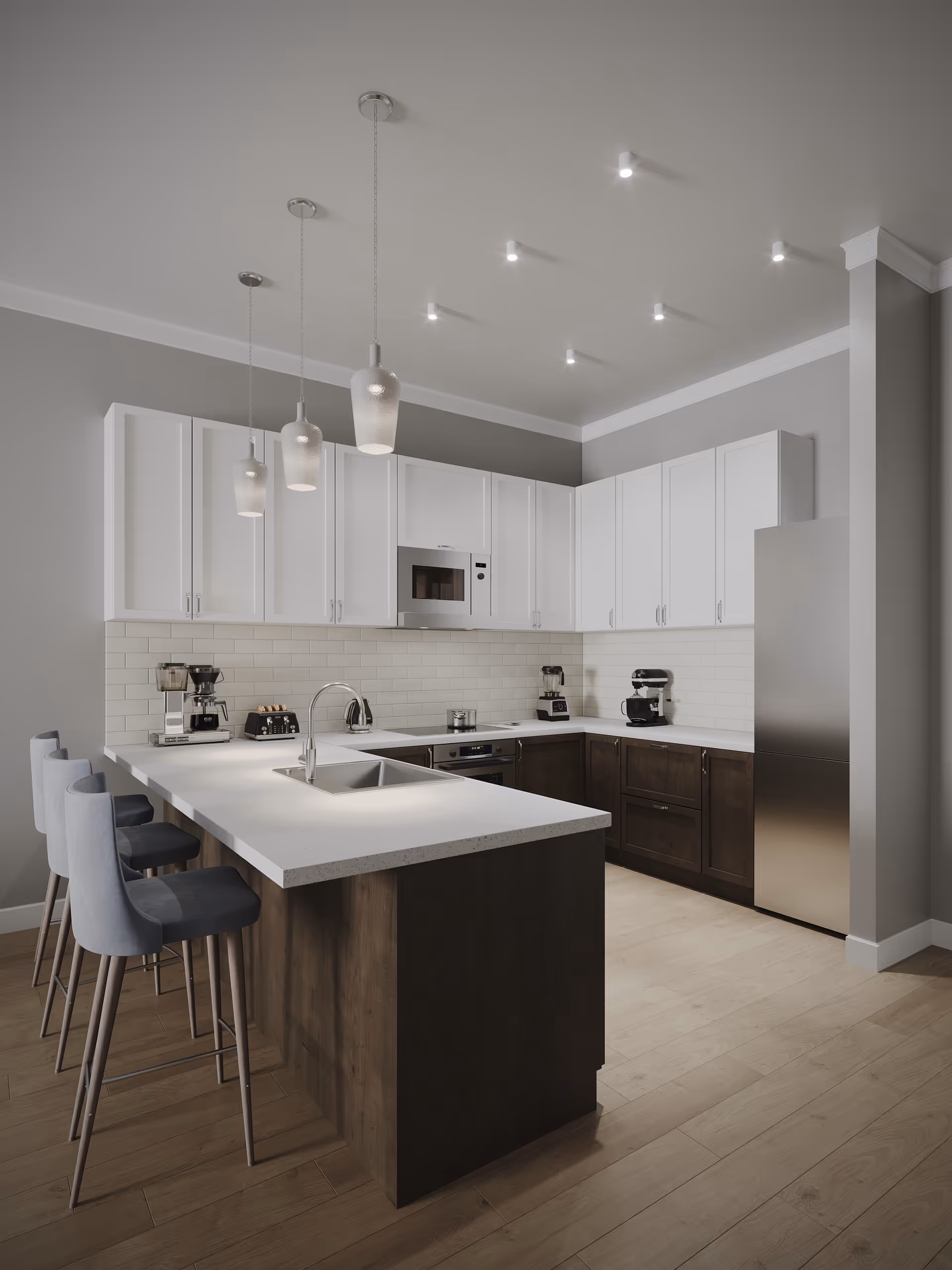 Modern kitchen with white upper cabinets and dark lower cabinets, a white island with a built-in sink, three blue cushioned bar stools, pendant lights hanging from the ceiling, and various kitchen appliances on the countertop.