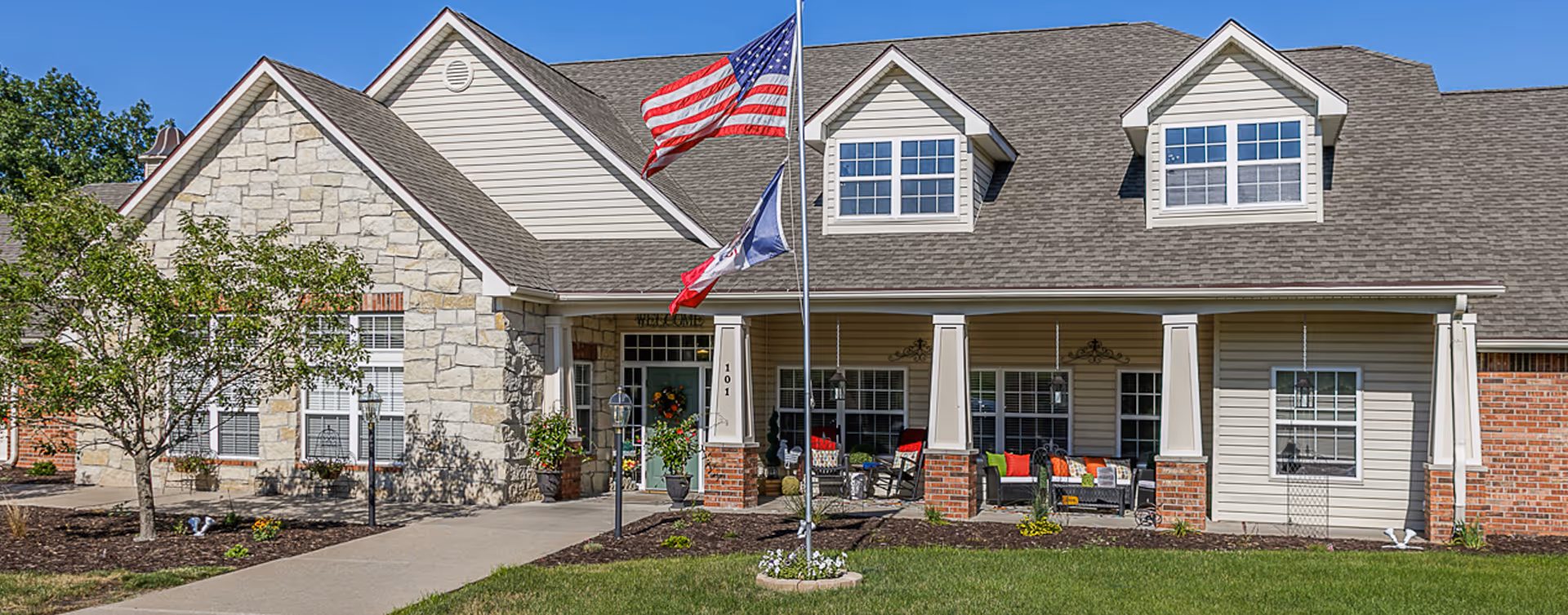 Front view of Bickford of Marshalltown facility with porch seating and flagpoles