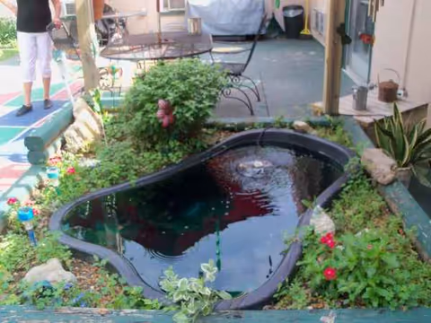 Outdoor courtyard at Benton Rehab & Health Care Center with a small pond, plants, and seating.