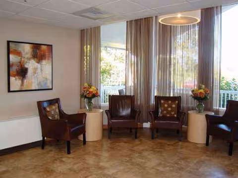 Indoor seating area with brown chairs, round tables, and floral arrangements.