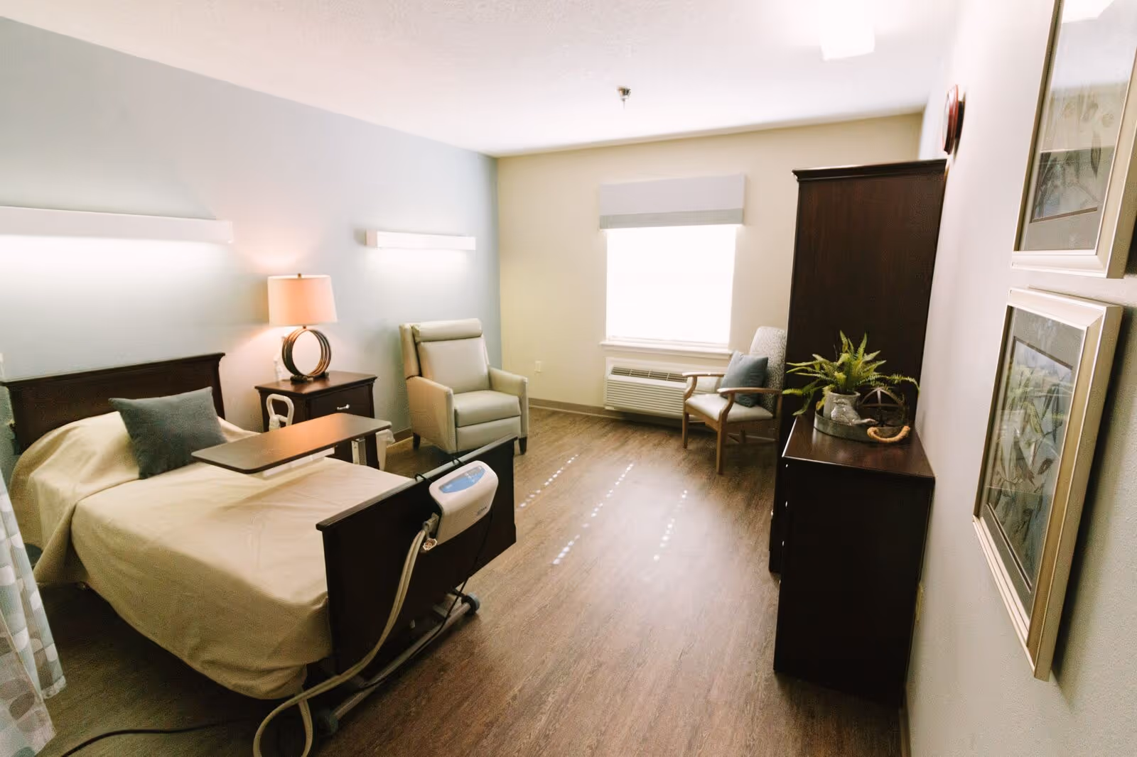 A bright senior living bedroom with a bed, seating area, and dresser.
