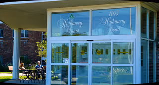 Front entrance of Hathaway Manor Extended Care with two residents seated outside.