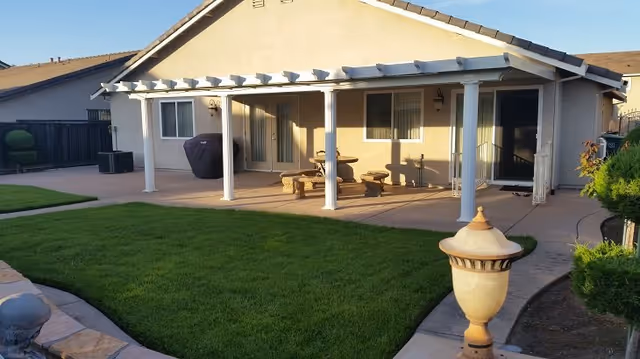 Backyard patio of a senior living home with a grass lawn and outdoor seating.
