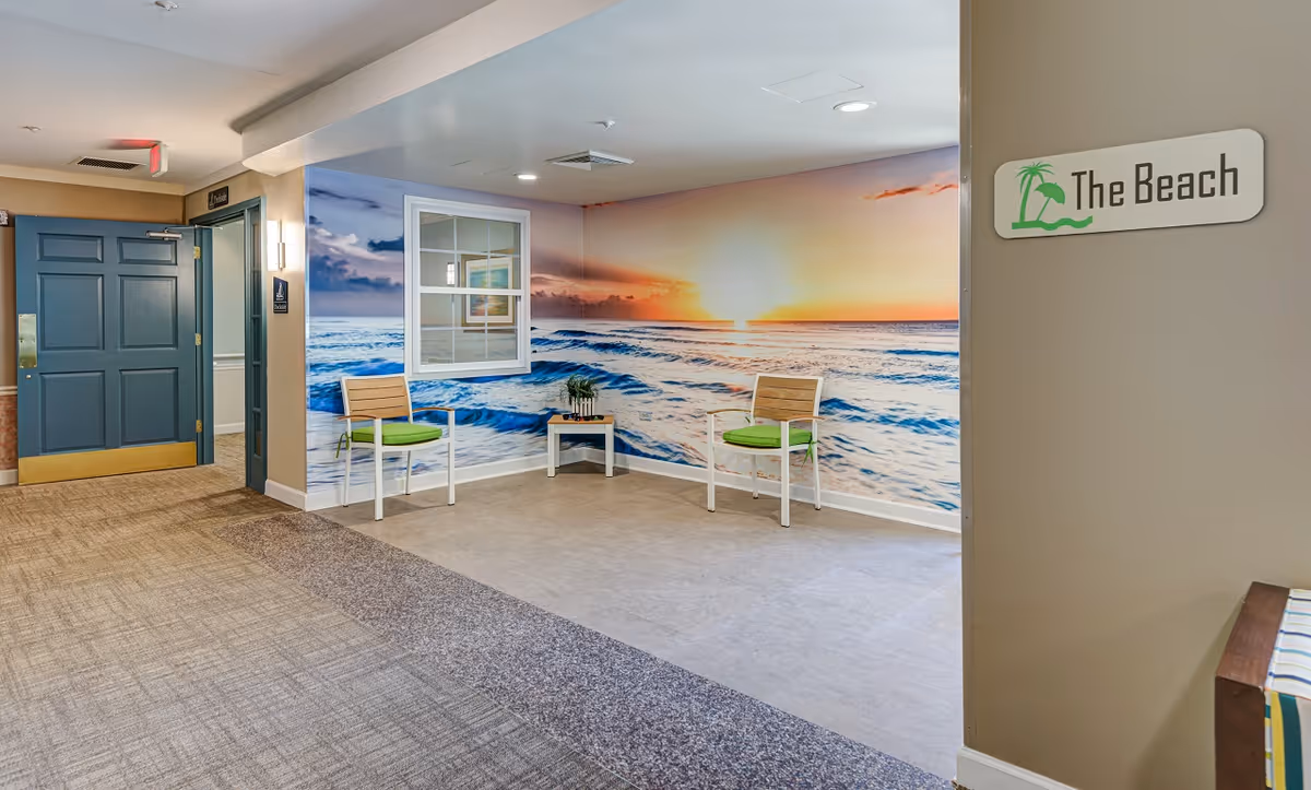 Hallway seating area with two chairs and a large ocean mural and a sign reading 'The Beach'.