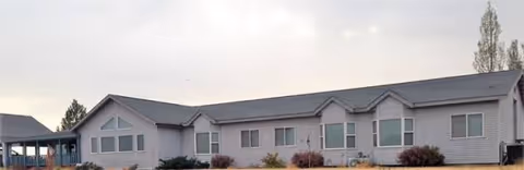 Long, single-story senior care facility exterior with multiple windows and shrubs.