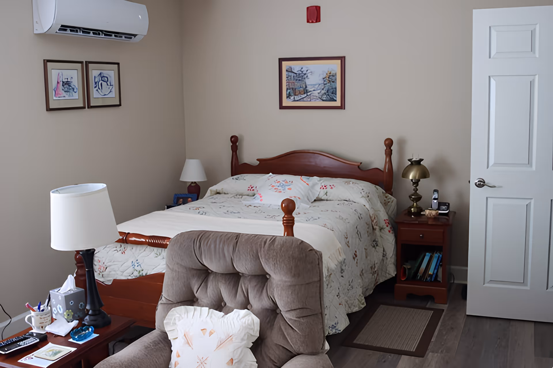 Cozy furnished bedroom with a wooden bed, upholstered armchair, nightstands, and lamps.