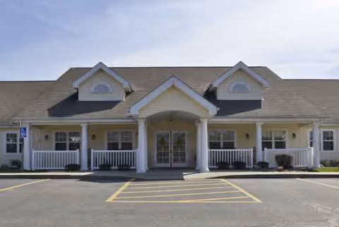 Single-story senior living facility with a covered entrance, white columns, and front parking.