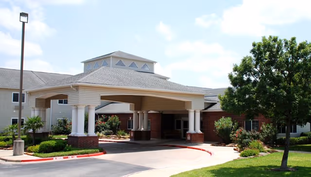 Front view of The Court at Round Rock facility entrance with driveway and landscaping.