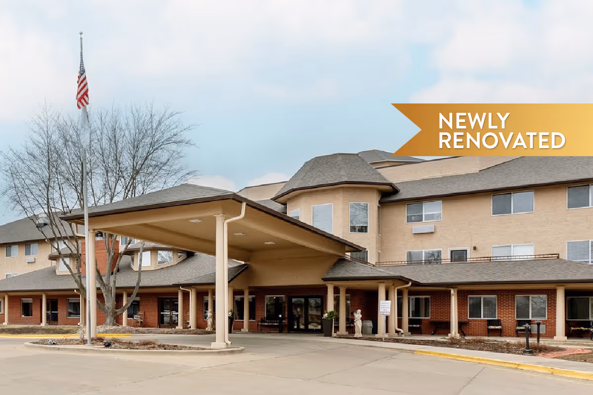 Exterior view of The Montvale Senior Living facility showing a large covered entrance with columns, a flagpole with an American flag, and a multi-story building with beige and brick facade under a cloudy sky. A banner in the top right corner reads 'NEWLY RENOVATED'.