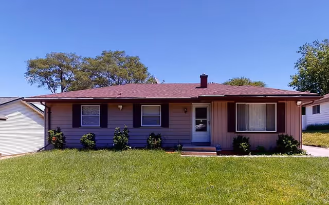 Single-story facility with brown siding, front entrance, and a grassy lawn.