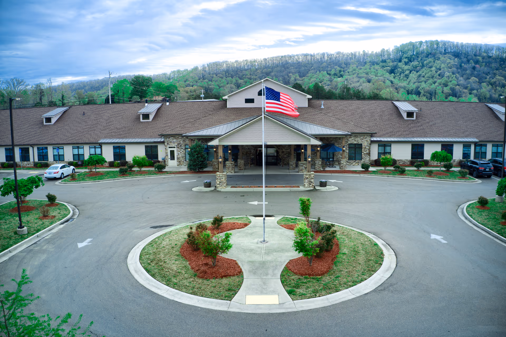 Exterior view of Blue Ridge Assisted Living and Memory Care with a flag pole and landscaped circular driveway.