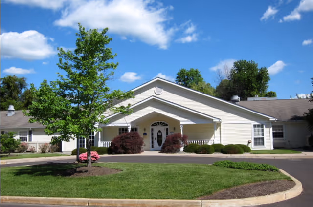Front view of Arden Courts Yardley senior living facility, with manicured lawn, shrubs, and trees.