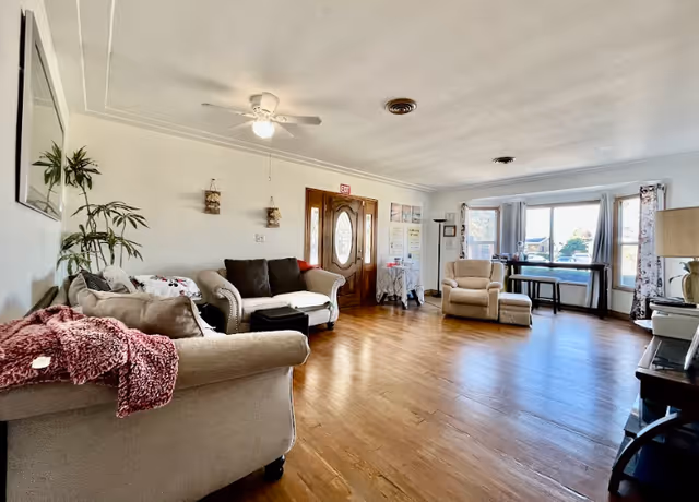Bright living area with sofas, an armchair, coffee table, and large windows.