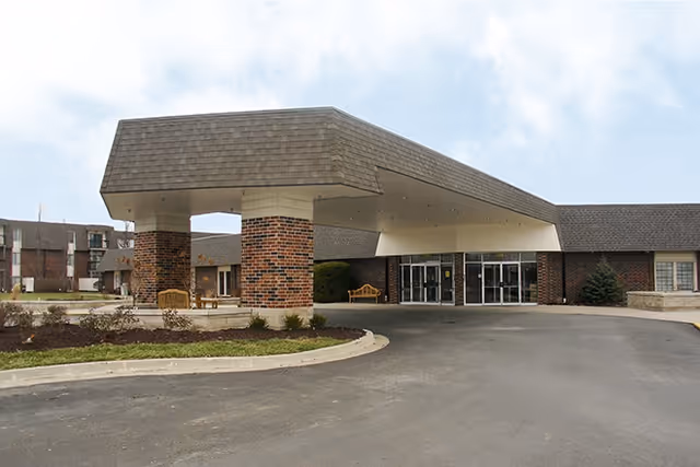 Front view of Foxwood Springs Senior Living entrance with brick columns and glass doors.
