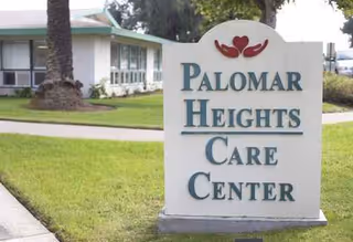 Outdoor scene with Palomar Heights Care Center sign near a building.