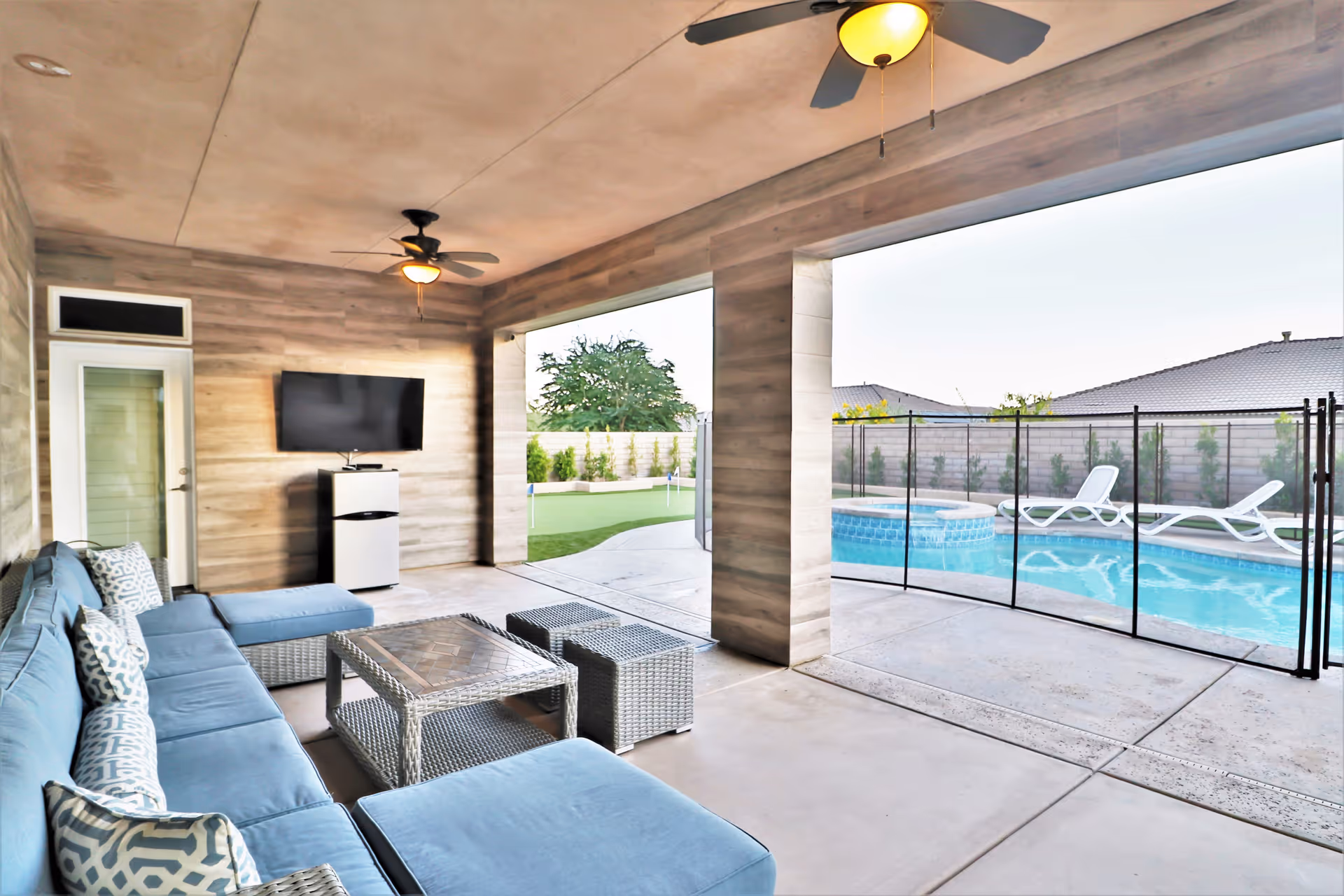 Covered outdoor seating area with a view of a swimming pool.