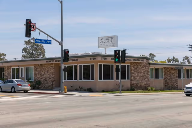 Exterior view of Atlantic Memorial Healthcare Center building at the corner of Atlantic Avenue, with traffic lights and cars on the street.