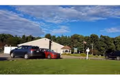Exterior view of Oil City Nursing and Rehabilitation facility with parked cars and green lawn.