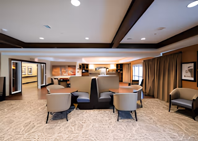 Spacious communal lounge with modern armchairs and booth seating under a coffered ceiling.