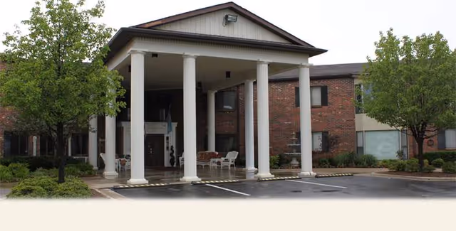 Brick building entrance with a covered portico and white columns at Golden Oaks Village.