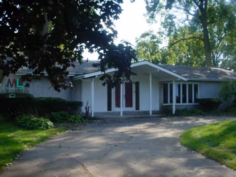 Single-story senior living facility front entrance with a driveway and trees.