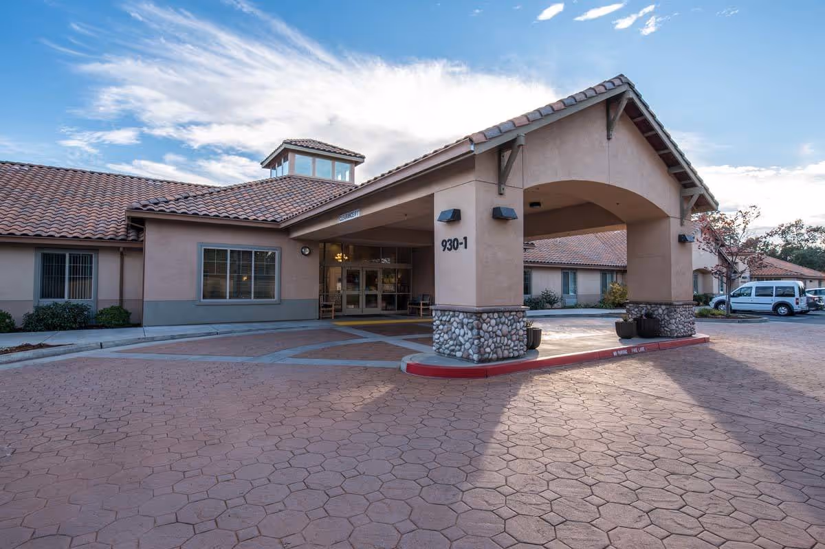 Covered entrance canopy and drive-up area in front of a single-story stucco building with a red tile roof.