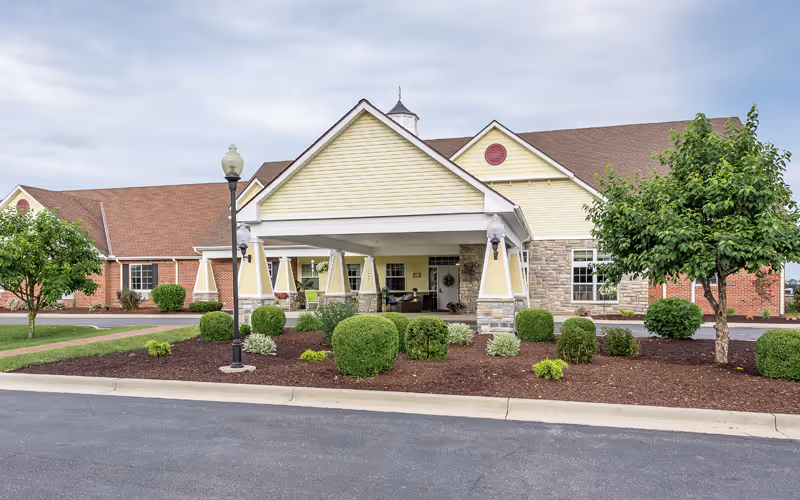 Exterior view of Bickford of Saginaw Township showing the covered entrance and landscaped shrubs.