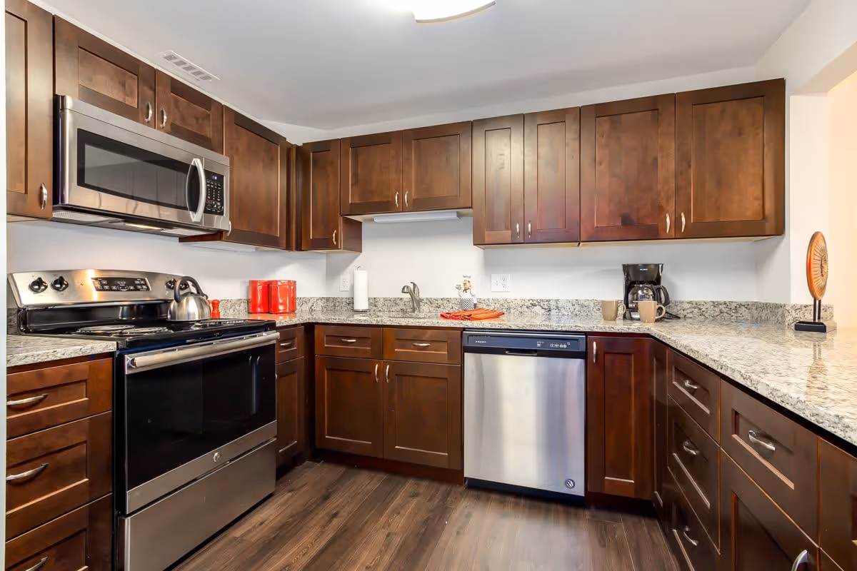 Modern kitchen with dark wood cabinets, stainless steel appliances, granite countertops, and wood flooring.