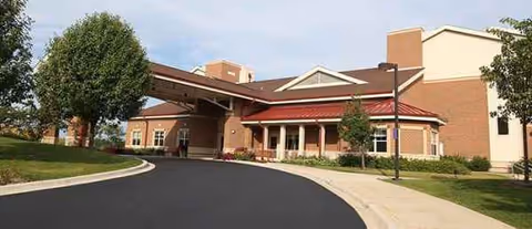 Brick senior living facility with curved driveway and covered entrance, Radford Green at Sedgebrook.