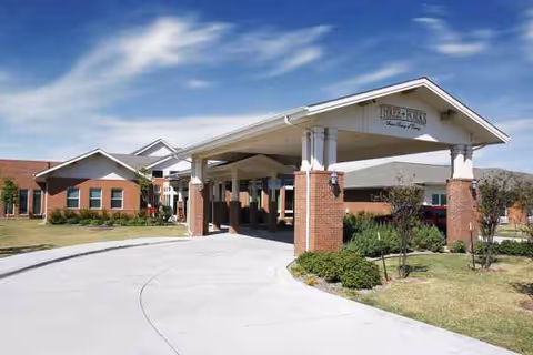 Exterior view of a senior living facility entrance with a covered drive and brick columns.