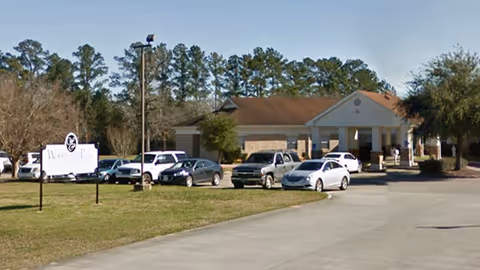 Exterior view of Woodland Park Nursing and Rehabilitation with cars parked in front.
