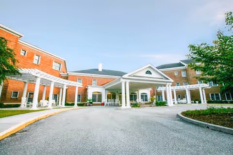 Front view of Champions Assisted Living entrance with white columns and curved driveway.