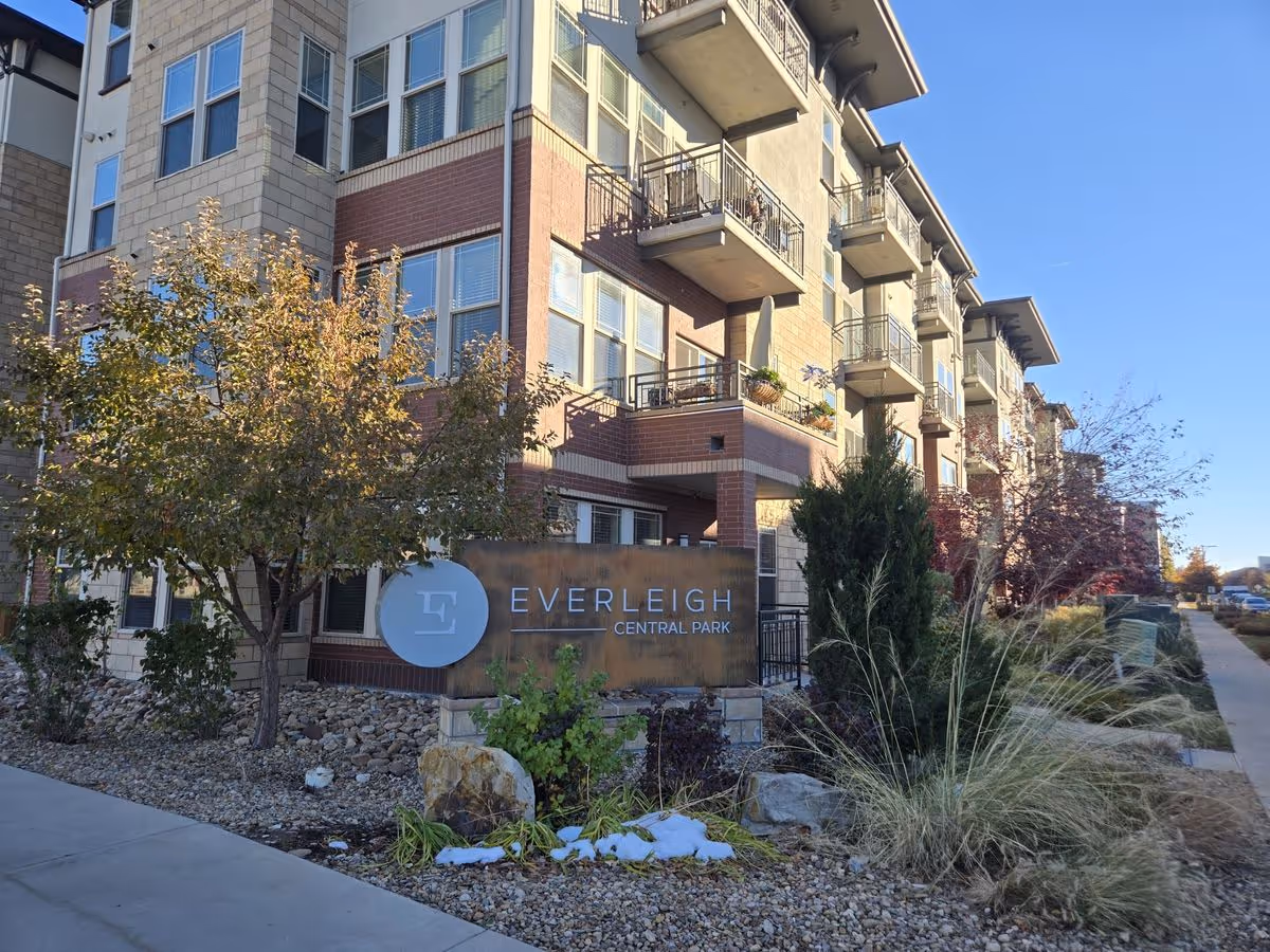 Front exterior of a multi-story Everleigh Central Park building with balconies and a landscaped entrance sign.