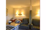A cozy nursing home living room with couches, chairs, a coffee table, and soft lighting.