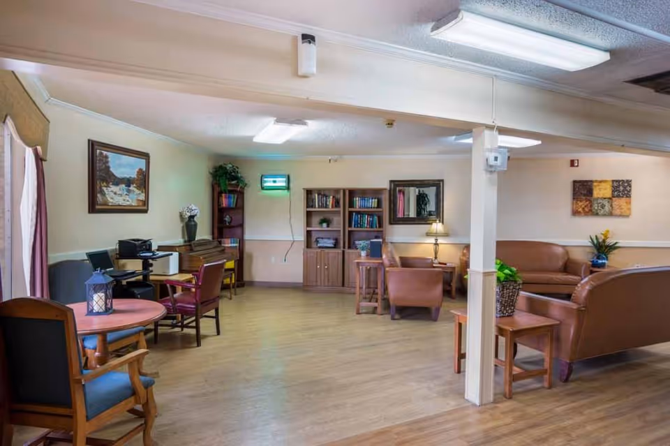 Communal lounge area with sofas, chairs, tables, bookshelves and soft lighting.