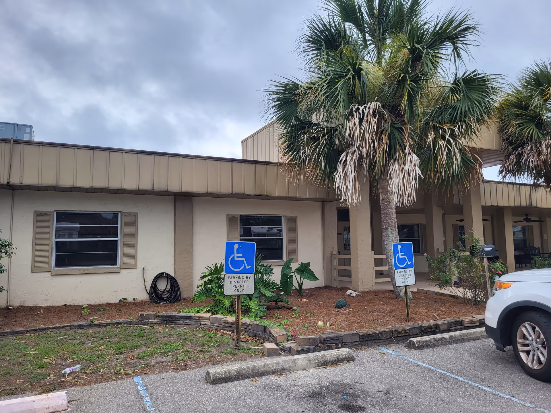 Exterior view of Shores Nursing and Rehab Center with palm trees and handicap parking.