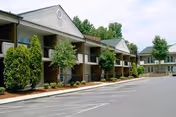 Exterior view of a senior living facility with balconies and a parking lot.