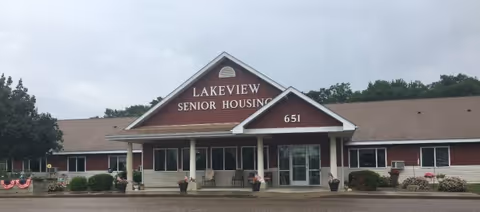 Front entrance of a single-story red building with a covered porch and a sign reading "Lakeview Senior Housing".